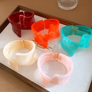 Detailed view of colorful irregular geometric twisted resin bracelets displayed in a tray