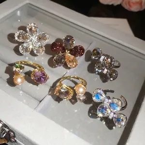 Elegant sparkling crystal butterfly and flower open rings displayed in a velvet jewelry box.
