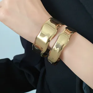 Close-up of irregular chunky gold-toned metal bangles with polished mirror finish