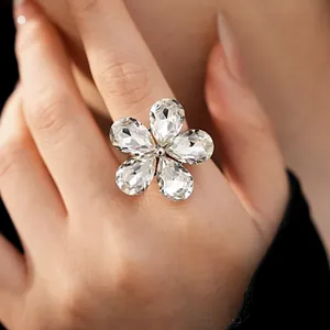 Detailed view of a stunning crystal flower open ring in silver on a model's hand.