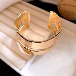 Detailed close-up of a minimalist gold-colored double-layer smooth metal cuff bracelet