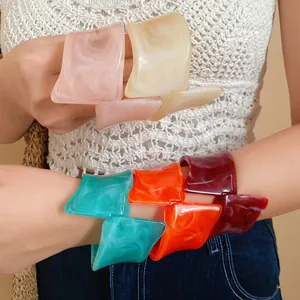 Close-up of colorful marbled resin irregular geometric twisted open bracelets on a model