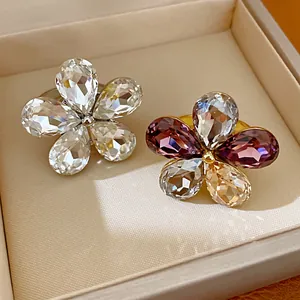 Detailed macro view of crystal flower rings in a premium box with elegant warm lighting