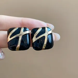 Macro view of vintage square drip oil earrings with gold abstract patterns