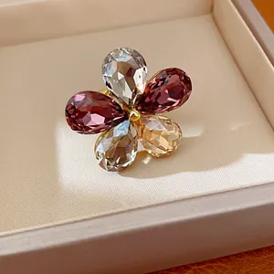 Close-up of a floral open ring with five pear-cut purple and clear crystals