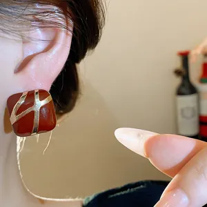 Close-up detail of vintage burgundy square oil-drop earrings with gold-toned accents