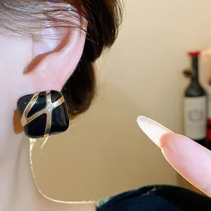 Close-up of vintage square black oil-dripping stud earrings with gold geometric pattern
