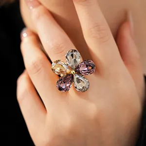 Detailed close-up of a golden flower ring with vibrant pear-shaped crystals on a hand
