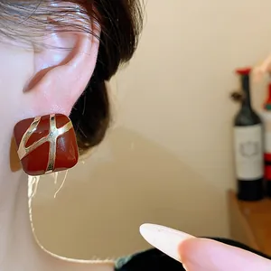 Close-up of retro square red enamel stud earring with gold detailing worn on ear