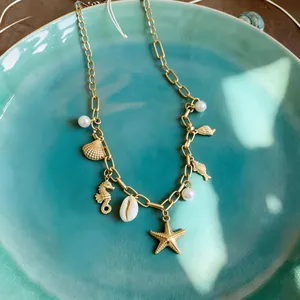 Detailed view of elegant gold ocean charms necklace with shells, starfish, and white pearls