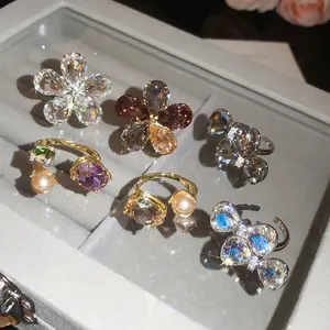 Close-up detail of various sparkling crystal floral and bow-tie open rings in a tray