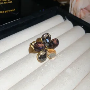 Detailed view of an elegant floral open ring with grey and amber crystals on white