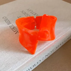 Macro detail of vibrant orange marbled resin bangle with unique twisted geometric design