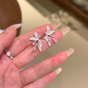 Gros plan de boucles d'oreilles fleurs élégantes avec détails en zircon et pétales blancs.