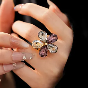 Detailed view of an oversized crystal flower ring on a hand with styled nails