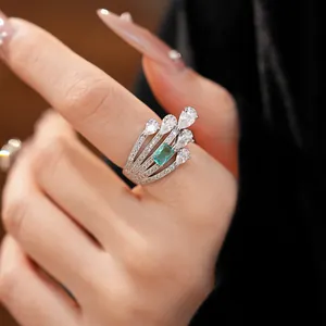 Close-up detail of an elegant multi-layer silver ring with white pear-cut and green stones.