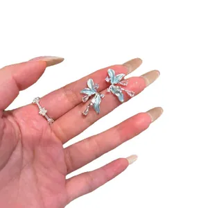 Élégantes boucles d'oreilles fleur en émail bleu avec cristaux de zircon sur main