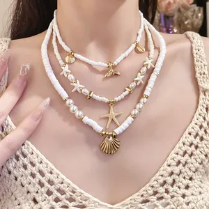 Detailed view of white clay bead and pearl necklace set with golden starfish and shell charms