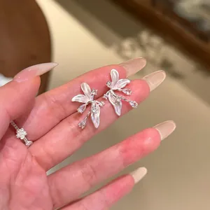 Gros plan détaillé de boucles d'oreilles fleurs à pétales blancs avec accents de zircon