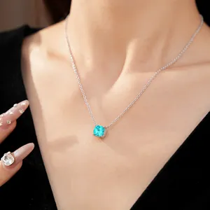 Close-up of a silver necklace with a cushion-cut cyan zircon pendant on a model.