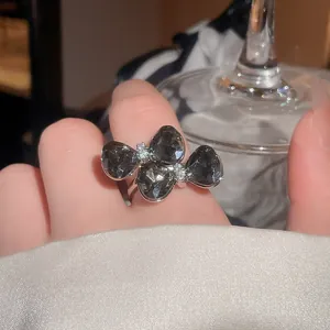 Detailed macro view of a luxury sparkling black bow-shaped flower open ring on a finger