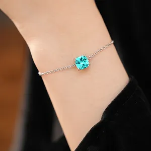 Detail shot of a minimalist silver chain bracelet with a square blue zircon gemstone