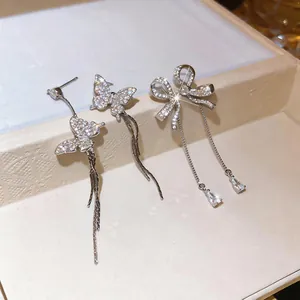 Close-up of zircon bow and butterfly tassel earrings with sparkling stone details