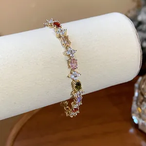 Detailed view of gold bracelet with multi-colored zircon flowers on display stand