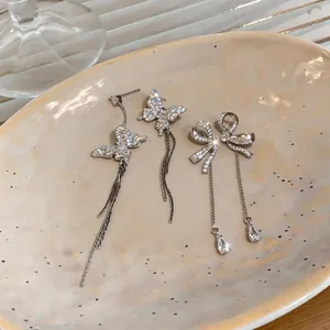 Close-up view of elegant zircon butterfly and bow tassel earrings with silver needles