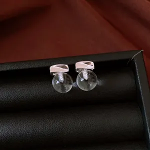 Eleganti orecchini a lobo in argento minimalisti con gocce sferiche trasparenti su vassoio nero