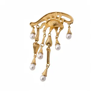 Spilla Evil Eye vintage in oro con eleganti nappe di perle bianche su sfondo bianco
