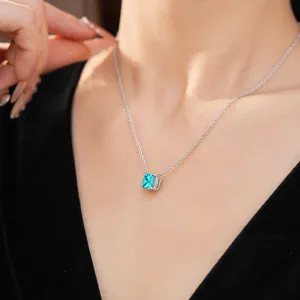 Close-up of a minimalist silver necklace with a square blue zircon pendant on neck