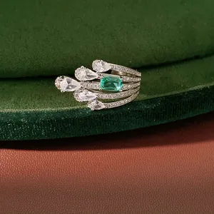 Close-up of a multi-layer silver ring with a green square zircon and pear-shaped stones.