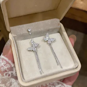 Macro view of sparkling zircon butterfly earrings with elegant silver long tassel detail