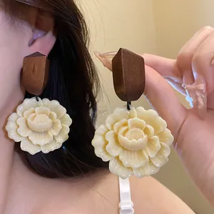 Detailaufnahme eleganter Harz-Blumenohrringe mit geometrischem Aufsatz aus dunklem Holz
