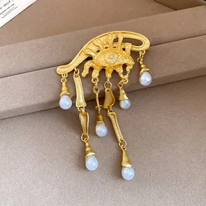 Primo piano di spilla vintage occhio del diavolo dorata con nappe di perle pendenti