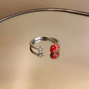 Dettaglio macro di un anello regolabile in argento con ciondolo fragola e stella.