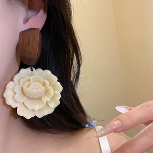Detailansicht eines Vintage-Harzblumen-Ohrrings mit geometrischem Holzoberteil am Modell.