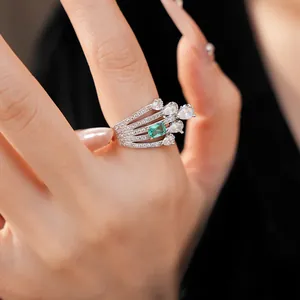 Macro detail view of elegant wave multi-band ring with emerald-cut green stone