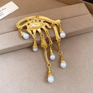 Primo piano di una spilla vintage a forma di occhio con nappe di perle bianche dorate.