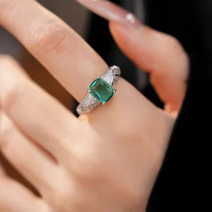 Detailed view of an emerald-cut green gemstone ring with a pavé crisscross band