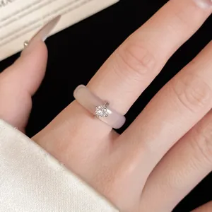 Detalle de un anillo minimalista de calcedonia con una piedra de circón redonda al dedo.
