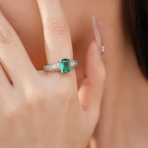Close-up detail of a luxury silver ring featuring a large emerald green cushion-cut gemstone