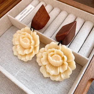 Detailansicht von Blumen-Resin-Ohrringen mit geometrischen Holz-Akzenten im Etui