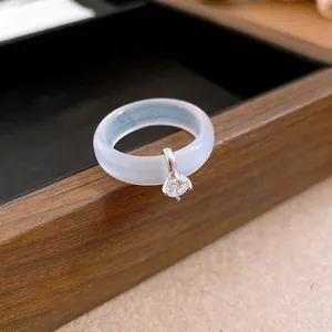 Primer plano de un anillo de calcedonia translúcida con un colgante de circón brillante