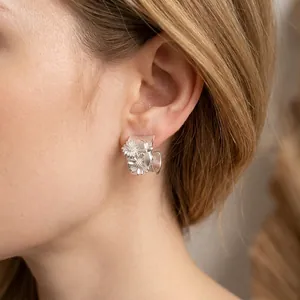 Elegantes pendientes de aro en forma de C con flores plateadas mate en una modelo