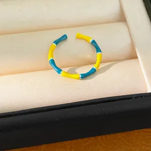Detail of bamboo-joint open ring featuring vibrant yellow and blue enamel finish