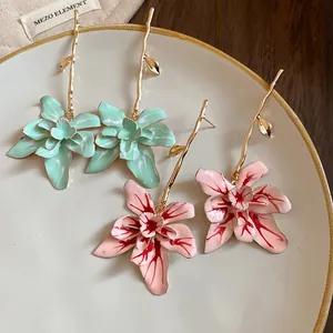 Detail of oil-drip flower drop earrings with branch stems on a ceramic plate.