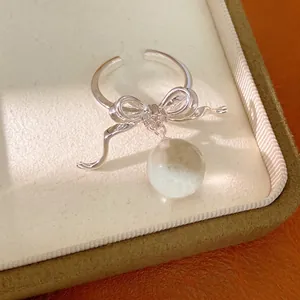 Elegant silver-toned bow open ring featuring zircon accents and a clear resin bead