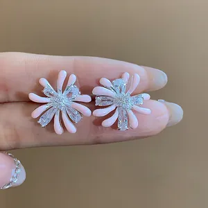 Close-up of pink enamel and zircon firework stud earrings with silver needles.